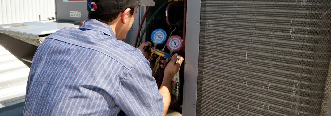 HVAC technician servicing a condenser unit in West Rockhill